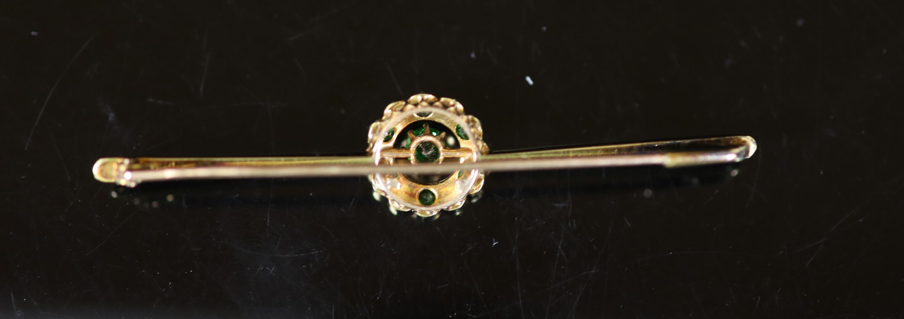 An early to mid 20th century gold, demantoid garnet and seed pearl circular cluster set bar brooch